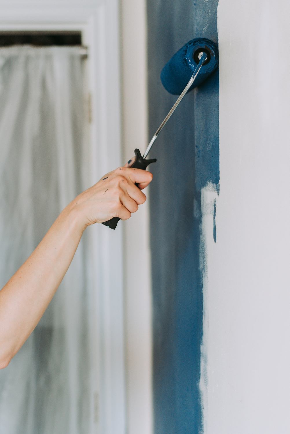 closeup-shot-person-using-paint-rollers-with-color-blue